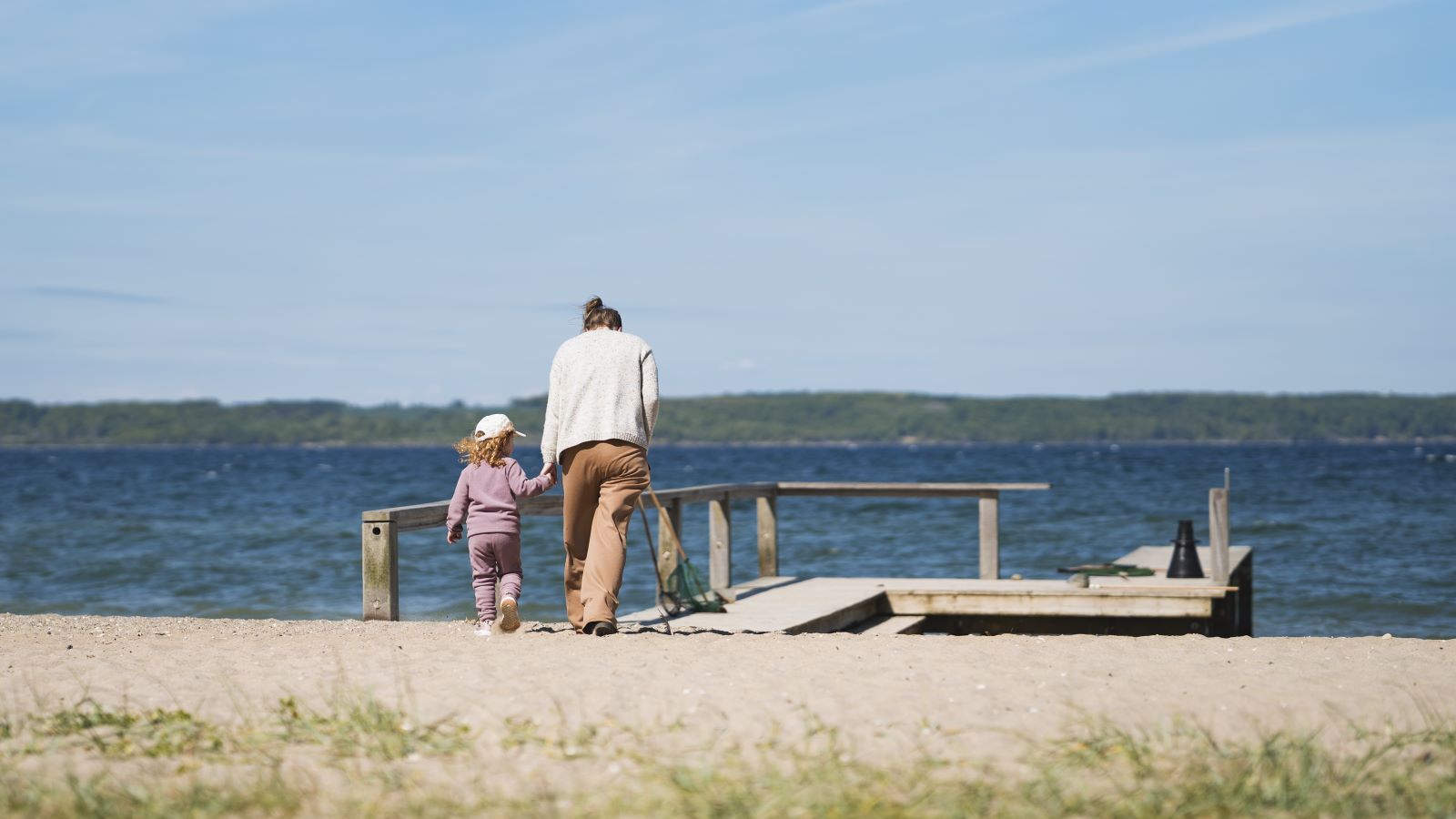 Mor og barn går på stranden på Trelde Næs
