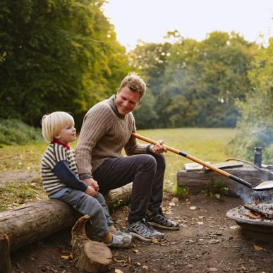 Far og søn sidder ved bålet på shelterplads